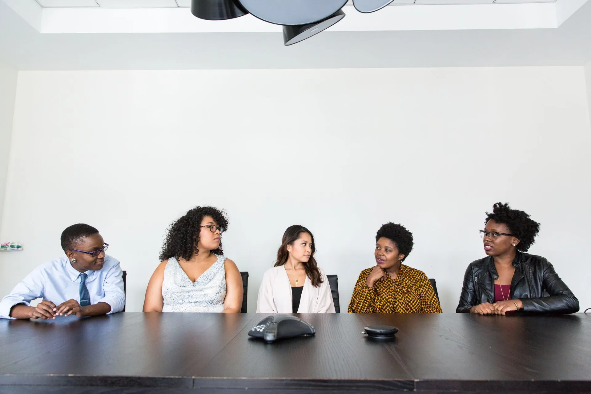 Five colleagues of different ages and backgrounds gathered around a conference table discussing a document