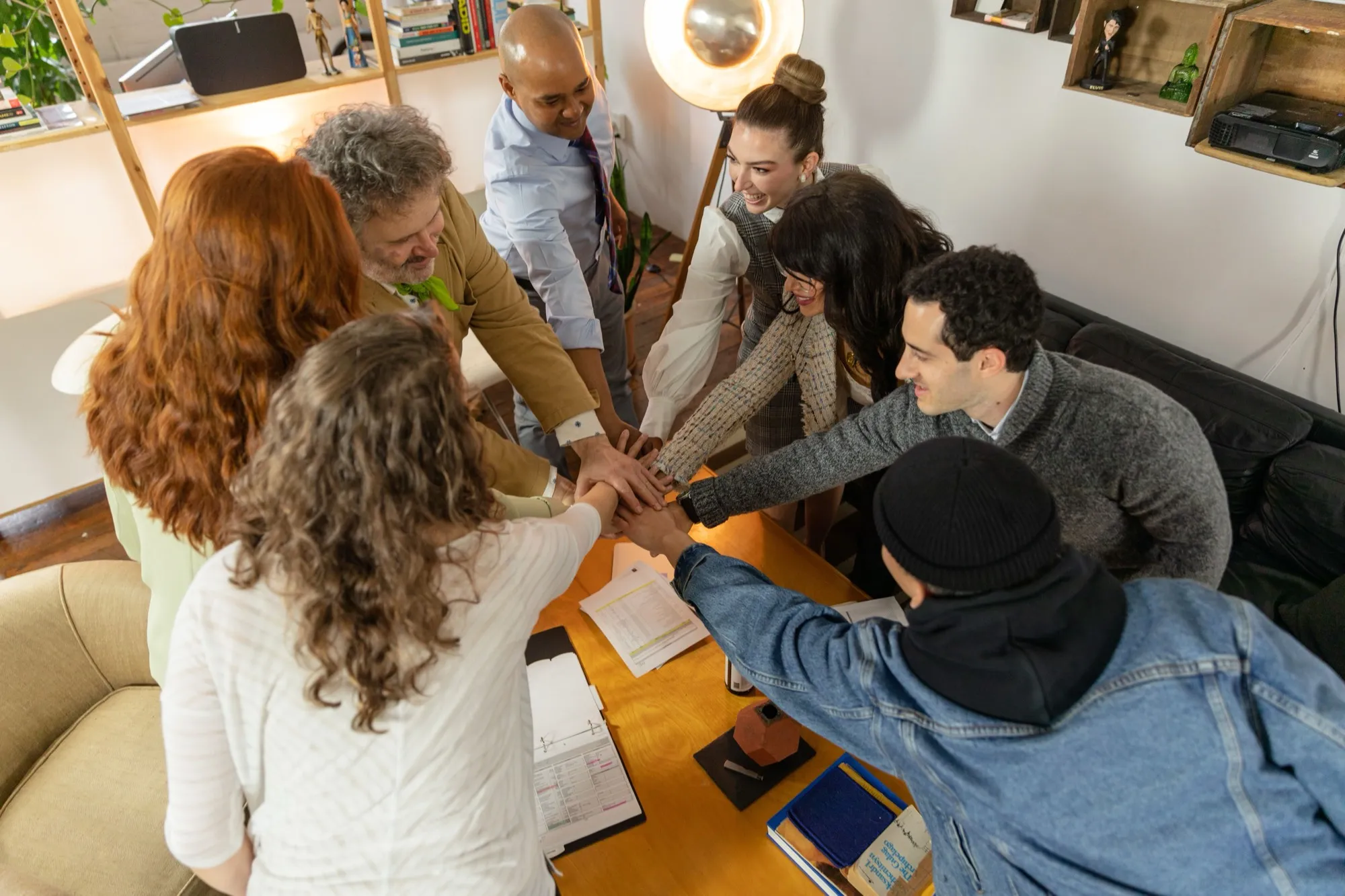 A team of colleagues bringing their hands together in a huddle in an office