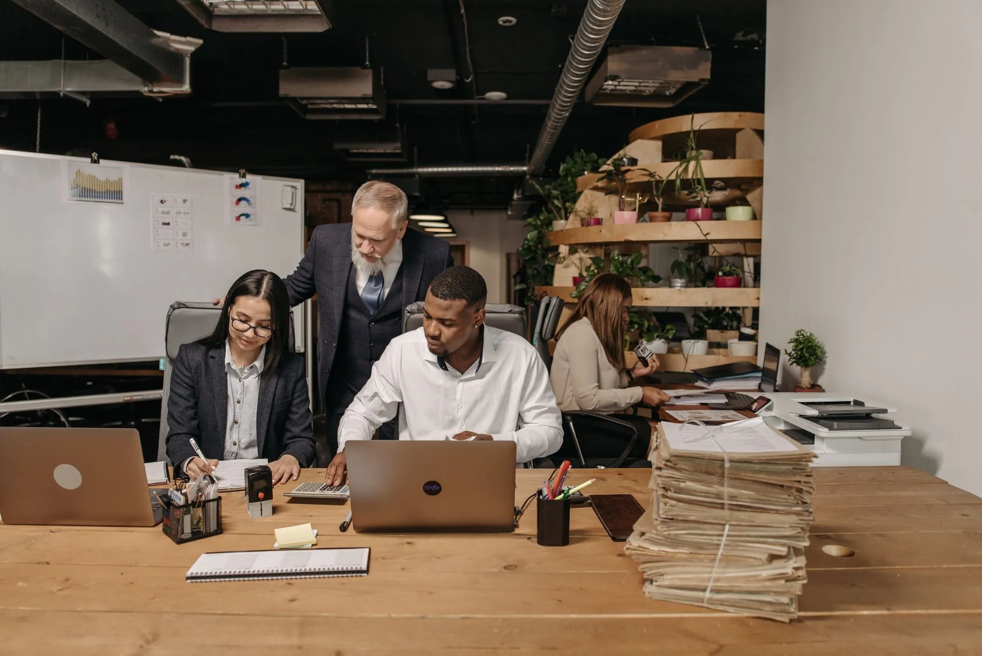 A small team of colleagues working together at a desk with laptops in an office